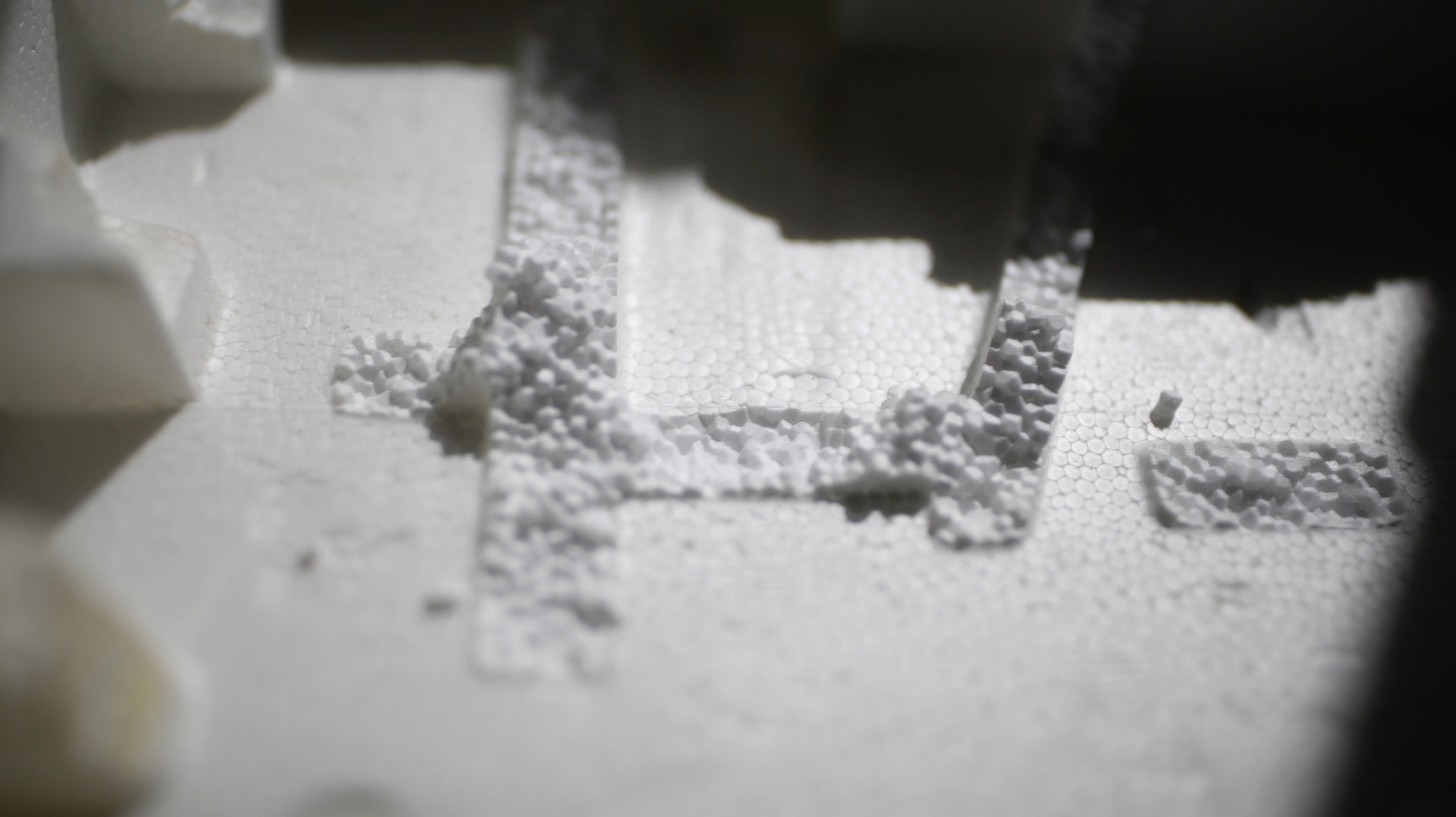 This horizontal image is a still from a film. It’s an extreme close-up shot of white Styrofoam.